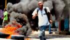 Haitian student running by burning tires amid protests