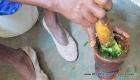 Cooking: A Haitian woman mashing up poireau (leek), with garlic and other spices in her pilon